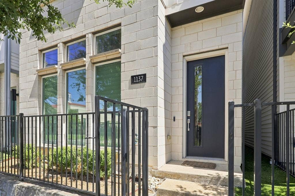 1137 Manderly Court, Dallas, TX 75204 Modern facade with light-toned masonry block, multiple windows, and a dark entry door with a vertical glass insert