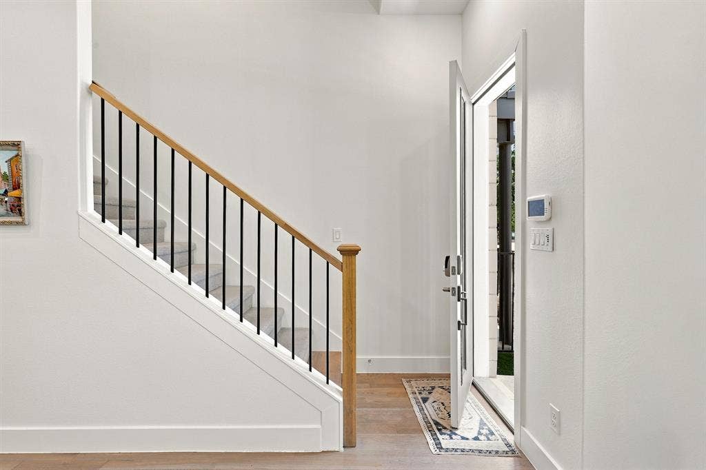 1137 Manderly Court, Dallas, TX 75204 Wood-finish flooring, white walls, and a modern white entry door with a sidelight