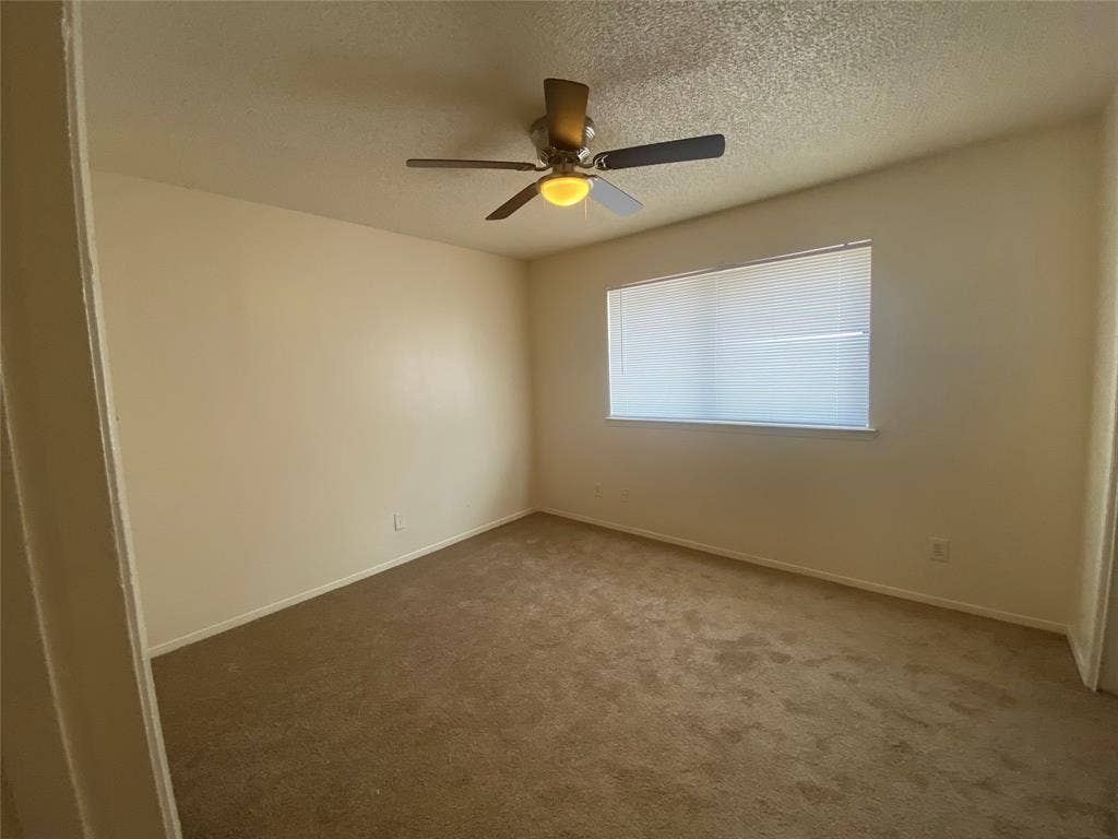 2802 Wimbledon Court, #B, Garland, TX 75041 Unfurnished room featuring carpet, a ceiling fan, baseboards, and a textured ceiling