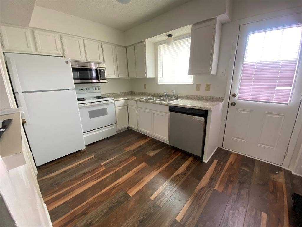2802 Wimbledon Court, #B, Garland, TX 75041 Kitchen featuring stainless steel appliances, light countertops, white cabinets, a sink, and dark wood-type flooring