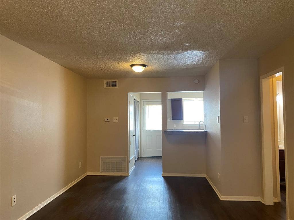 2802 Wimbledon Court, #B, Garland, TX 75041 Spare room with a textured ceiling, visible vents, baseboards, and dark wood-type flooring