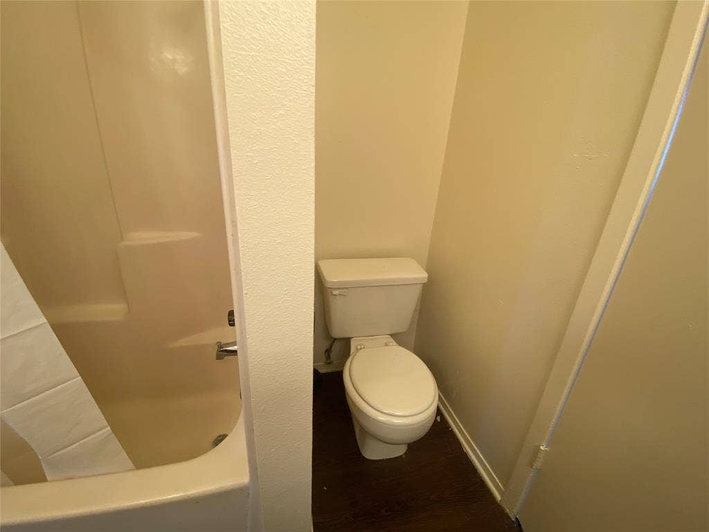 2802 Wimbledon Court, #B, Garland, TX 75041 Full bathroom featuring a washtub, baseboards, walk in shower, toilet, and wood finished floors