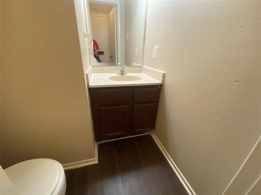 2802 Wimbledon Court, #B, Garland, TX 75041 Half bath featuring baseboards, wood finished floors, toilet, and vanity