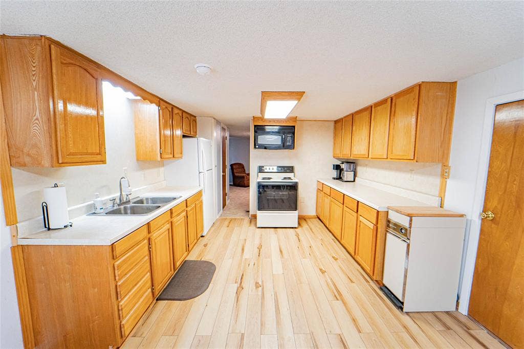 Kitchen featuring extensive wood-finish cabinetry, white countertops, and wood-finish flooring