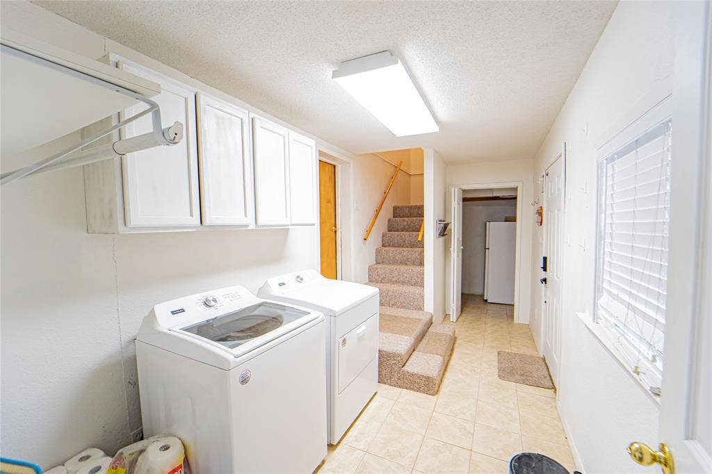 Utility area featuring tiled flooring, built-in cabinetry, and a window with blinds