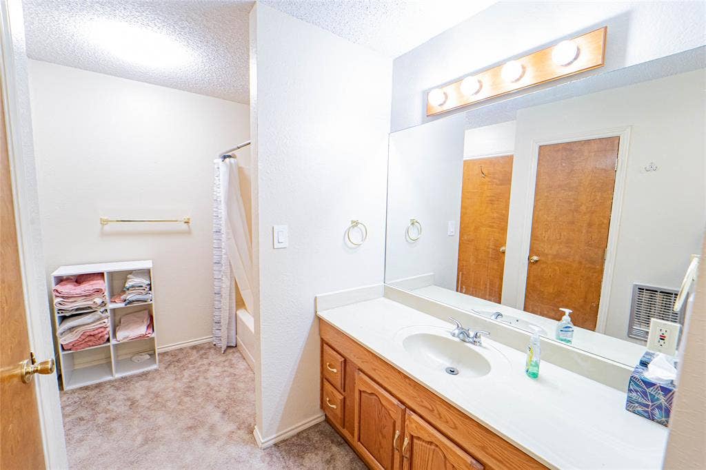 White vanity with integrated sink, wood-finish cabinetry, and a large wall-mounted mirror