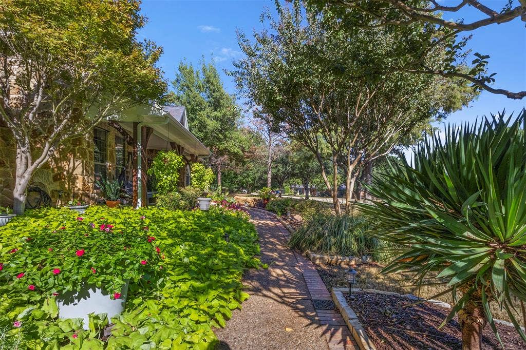 15600 Big Horn Trail, Frisco, TX 75035 Stone exterior with a covered porch, brick pathway, and mature trees