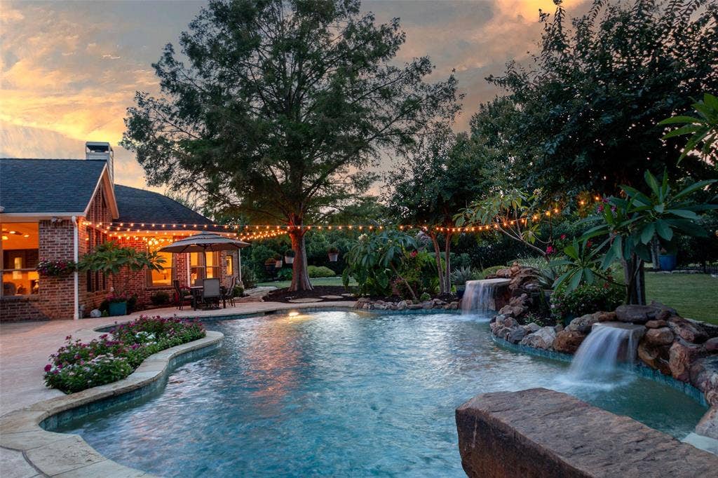 15600 Big Horn Trail, Frisco, TX 75035 Freeform swimming pool with multiple waterfalls, extensive surrounding hardscaping, and mature landscaping