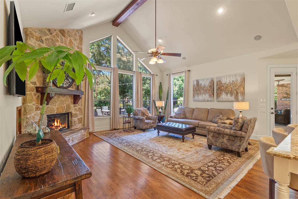 15600 Big Horn Trail, Frisco, TX 75035 Vaulted ceiling with exposed wood beams, stone fireplace, large picture windows, wood-finish flooring, and recessed lighting