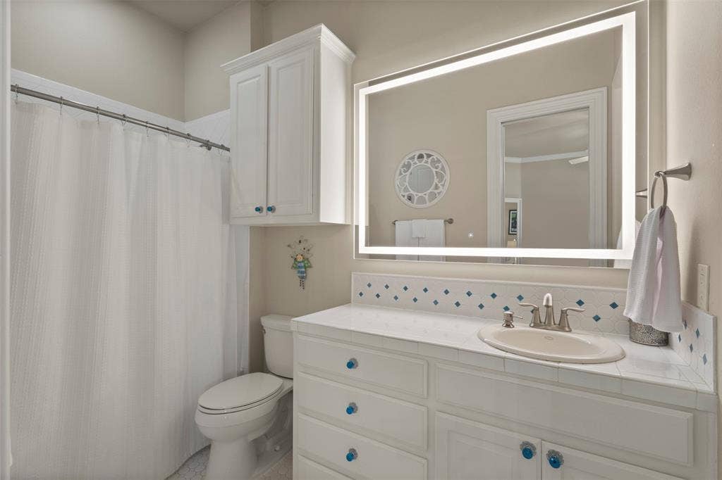 15600 Big Horn Trail, Frisco, TX 75035 Vanity with an integrated sink, illuminated mirror, and white cabinetry