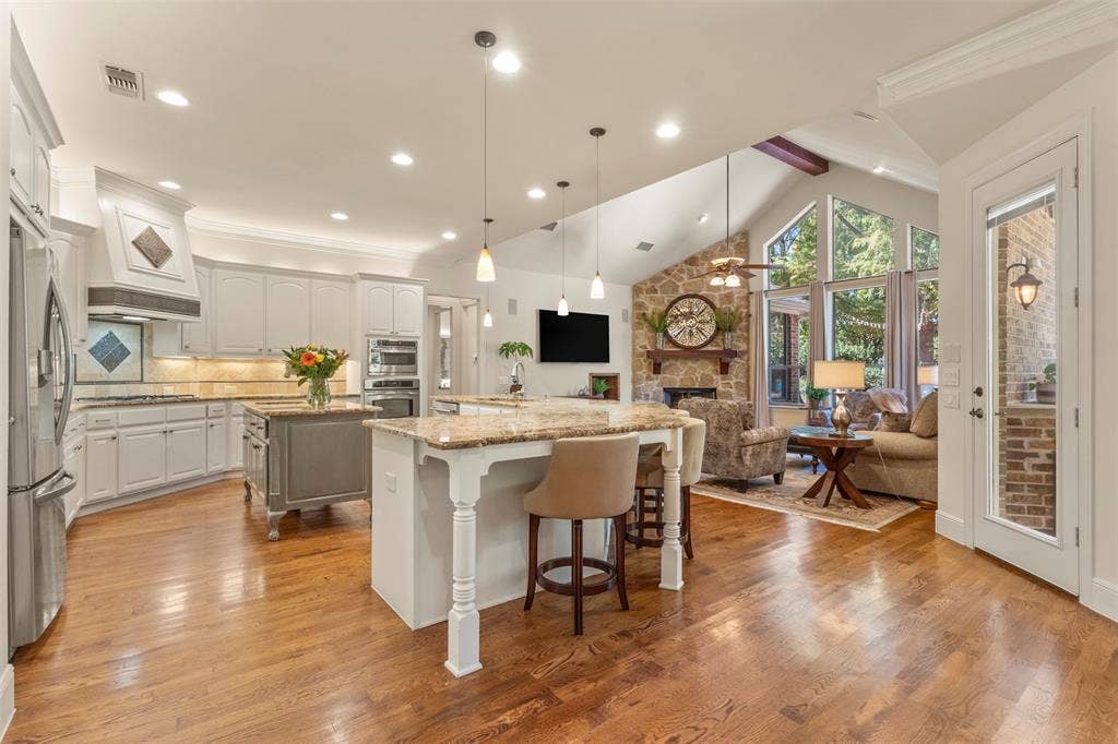 15600 Big Horn Trail, Frisco, TX 75035 Hardwood flooring with a vaulted ceiling, stone-faced fireplace, and built-in double ovens