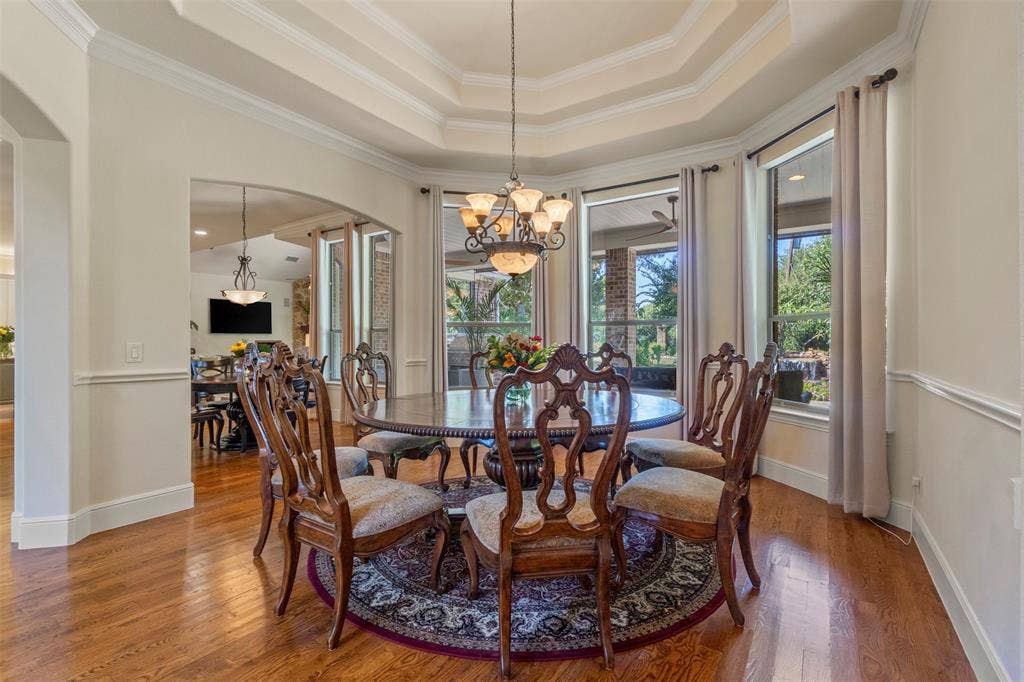 15600 Big Horn Trail, Frisco, TX 75035 Hardwood flooring, arched entryway, tiered tray ceiling, decorative chandelier, and extensive crown molding