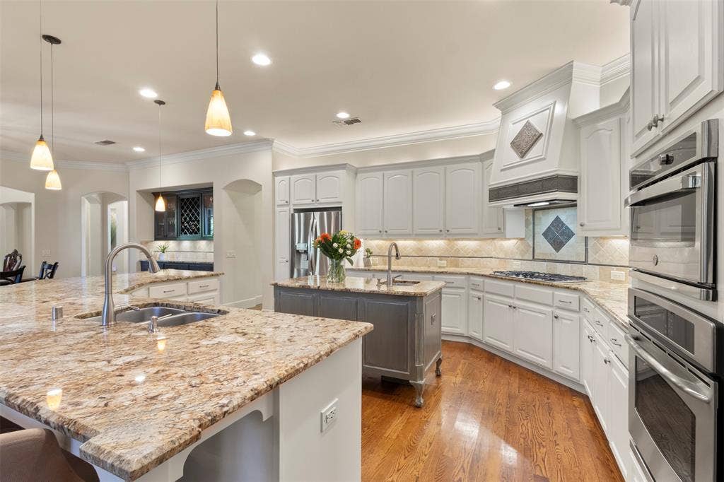 15600 Big Horn Trail, Frisco, TX 75035 Kitchen with light-toned cabinetry, a spacious island with a double basin sink, and wood-finish flooring
