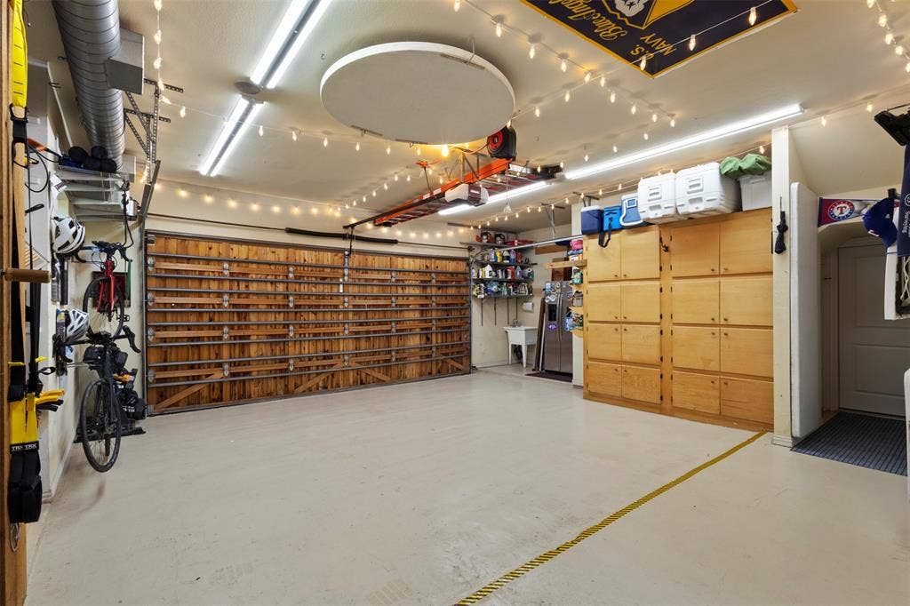 15600 Big Horn Trail, Frisco, TX 75035 Spacious garage with light-toned flooring, extensive built-in cabinetry, and a utility sink