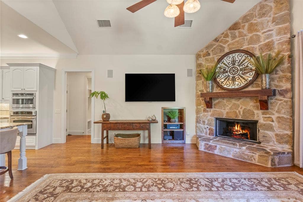 15600 Big Horn Trail, Frisco, TX 75035 Warm wood-finish flooring, a stone-clad fireplace with a wood mantel, and vaulted ceilings