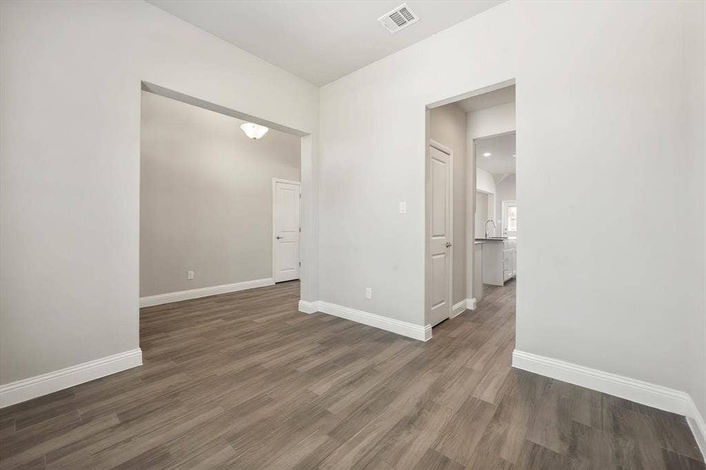 3636 Wintergreen Street, Grand Prairie, TX 76065 Spacious interior featuring pristine white walls, wood-look tile flooring throughout, and abundant natural light from recessed ceiling fixtures