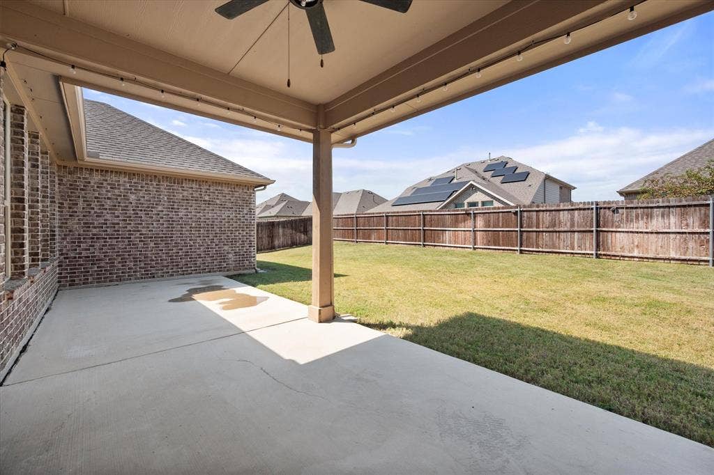 3636 Wintergreen Street, Grand Prairie, TX 76065 Covered patio with a ceiling fan, string lighting, and direct access to the expansive backyard featuring a wood fence and manicured lawn