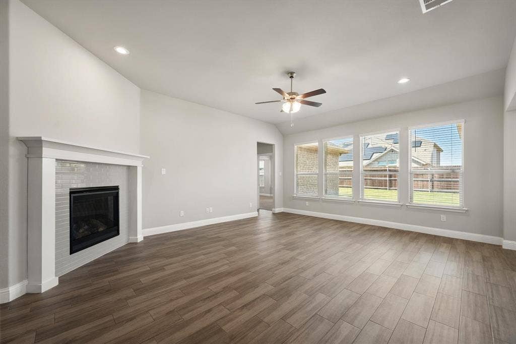 3636 Wintergreen Street, Grand Prairie, TX 76065 Spacious living room showcasing warm wood-finish flooring, recessed ceiling lighting, and a ceiling fan