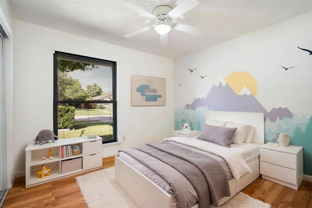 Bedroom featuring wood-finish flooring, a ceiling fan with integrated lighting, and a large window with a dark frame