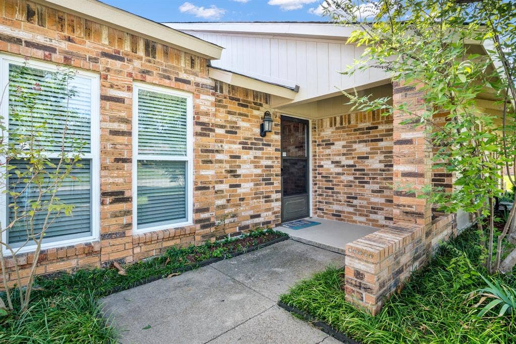 Multi-toned brick facade, covered entryway, concrete walkway, and low-maintenance landscaping