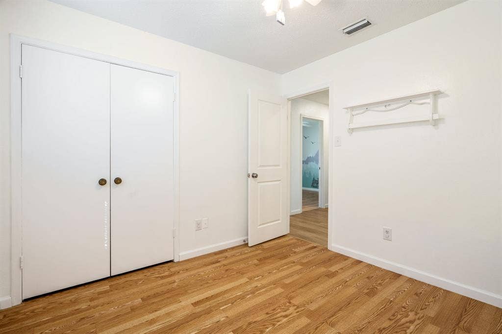 Wood-finish flooring, double-door reach-in closet, and attached wall-mounted shelving unit