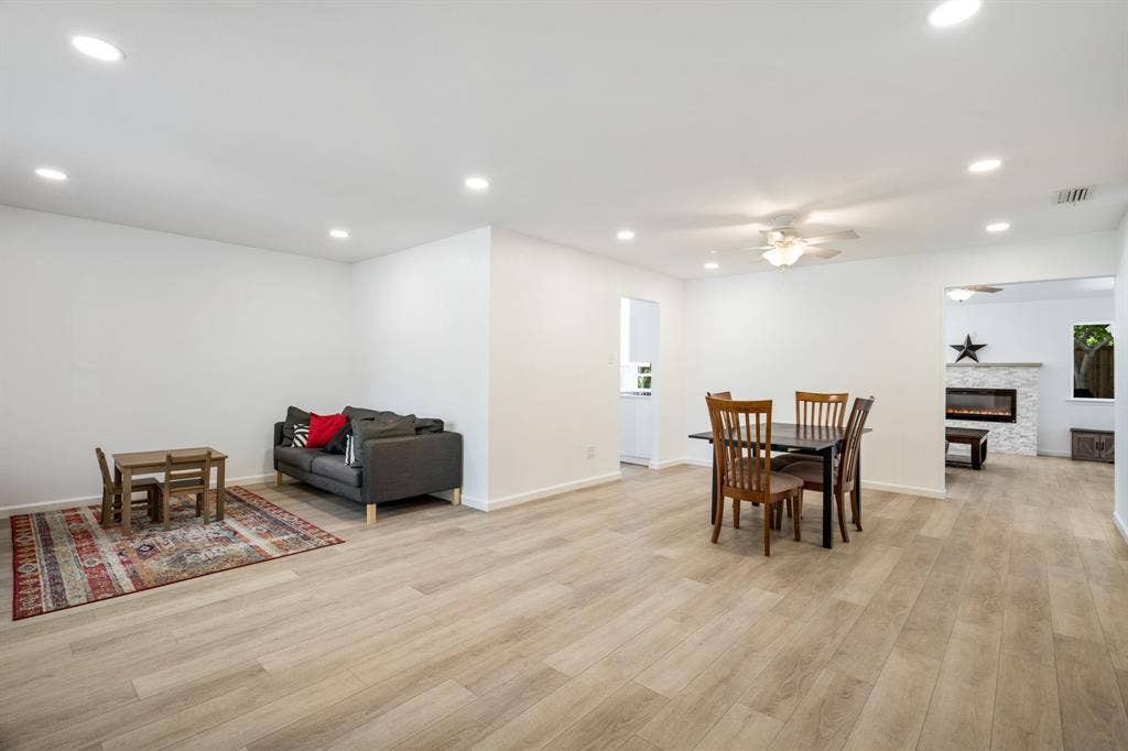 Open-concept interior featuring light wood-finish flooring, recessed lighting, and a stone-clad electric fireplace