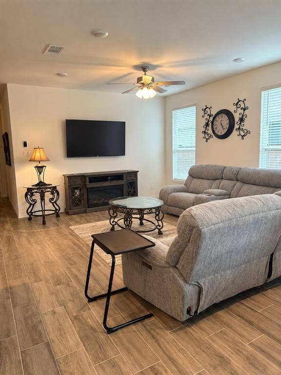 5719 Huffines Boulevard, Royse City, TX 75189 Wood-finish flooring, recessed lighting, ceiling fan, multiple windows with blinds, and a built-in media console with an integrated fireplace