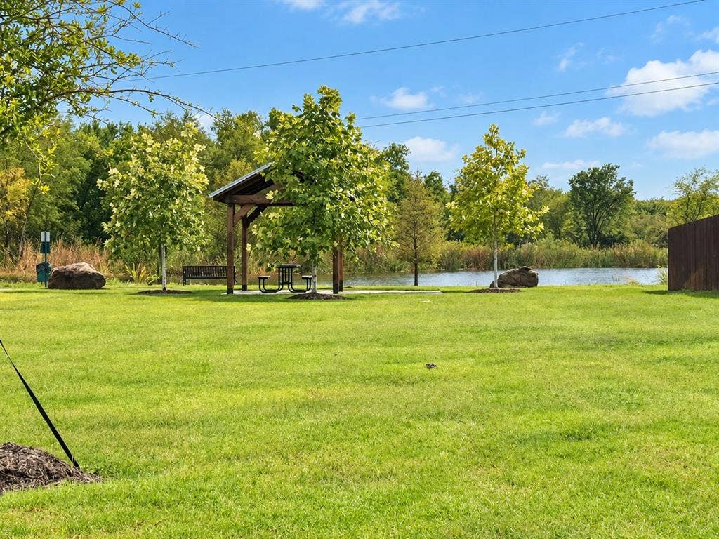 5719 Huffines Boulevard, Royse City, TX 75189 Expansive green lawn with mature trees, a covered picnic area, and a tranquil pond