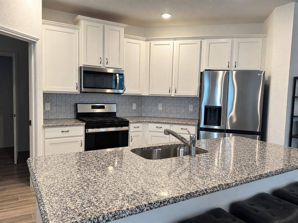 5719 Huffines Boulevard, Royse City, TX 75189 Kitchen featuring white shaker cabinetry, stainless steel appliances, patterned tile backsplash, and granite countertops