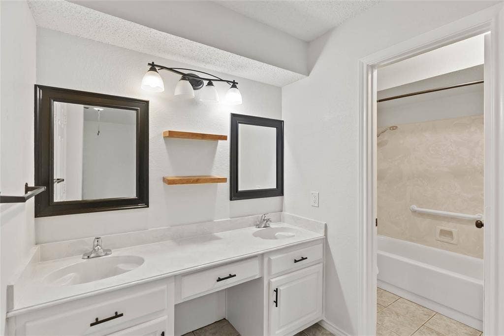 Dual vanity with white cabinetry, integrated sinks, and individual framed mirrors