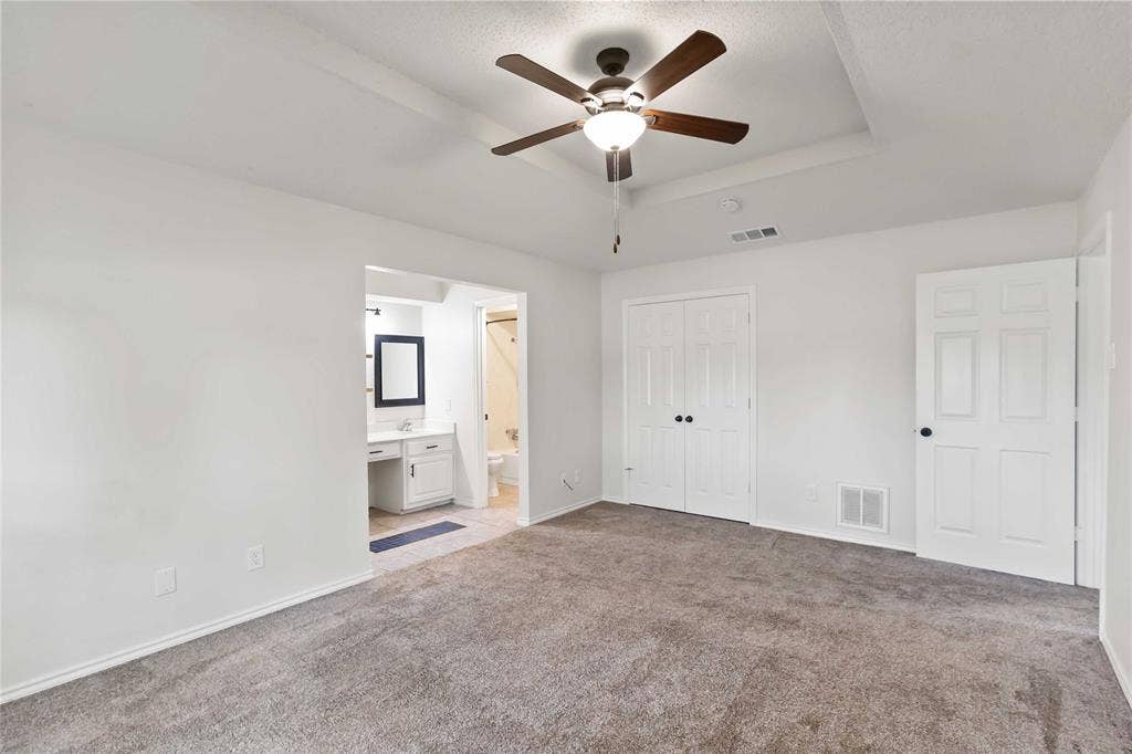 Spacious bedroom featuring plush gray carpeting and white walls