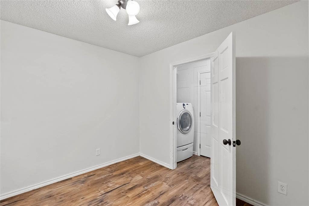 Room featuring wood-finish flooring, white walls, and a white ceiling with a flush-mount light fixture