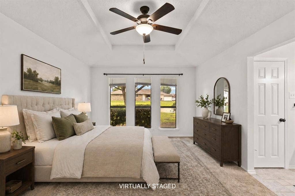Spacious bedroom with a tray ceiling and a ceiling fan with light fixture