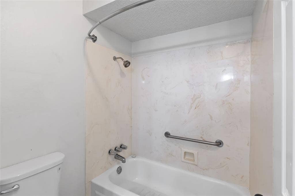 Full bathtub with chrome fixtures, a curved shower rod, and a shower head