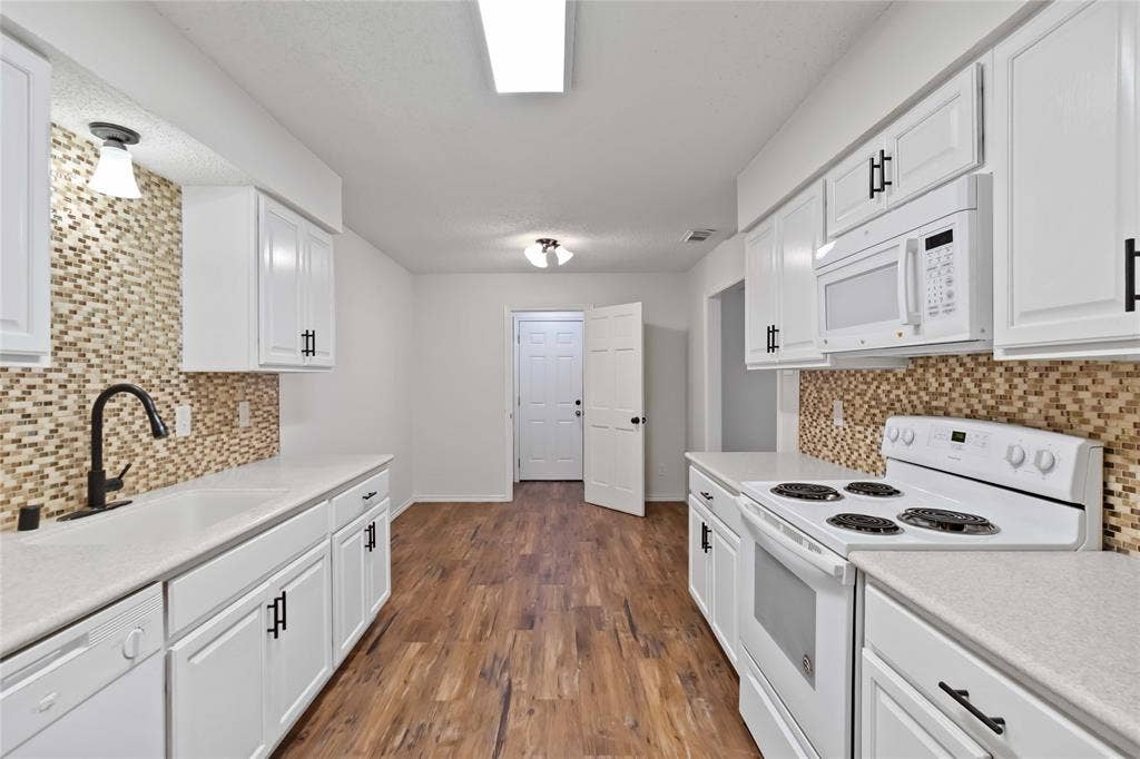 Kitchen featuring white cabinetry, light countertops, wood-finish flooring, and a mosaic tile backsplash
