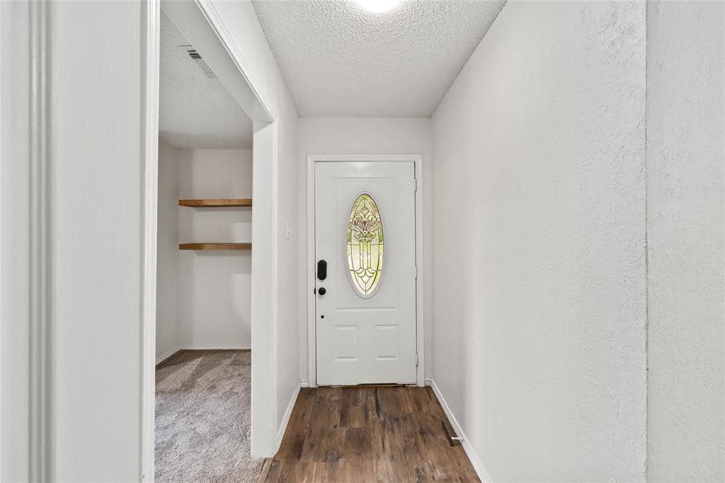 Entryway featuring wood-finish flooring, a white door with decorative glass insert, and neutral wall tones