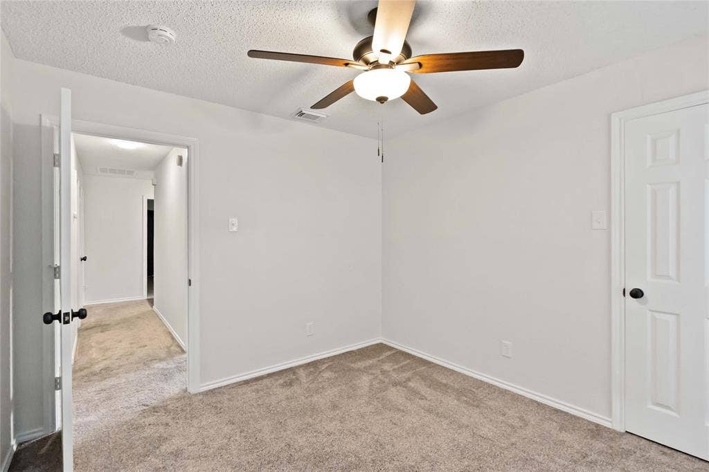 Carpeted room with a ceiling fan light fixture, white walls, and white trim
