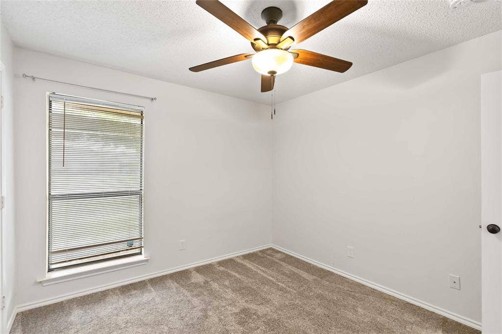 Bedroom featuring neutral carpeting, a double-hung window with blinds, and a ceiling fan with integrated lighting