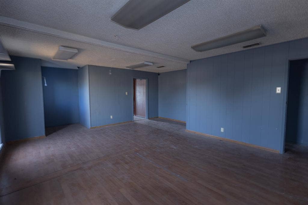 1723 W Waco Drive, #1725, Waco, TX 76707 Expansive room featuring wood-finish flooring, blue paneled walls, and fluorescent ceiling lighting