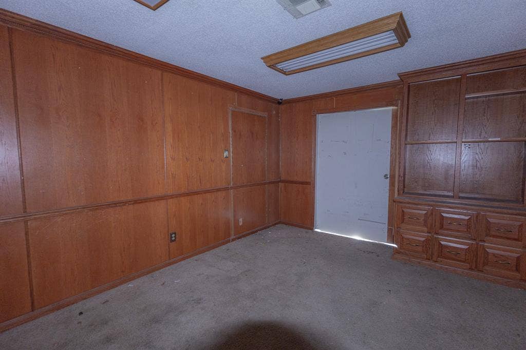 1723 W Waco Drive, #1725, Waco, TX 76707 Wood paneling throughout, built-in wooden cabinetry with multiple drawers and glass-front upper cabinets, and a drop ceiling with a fluorescent light fixture