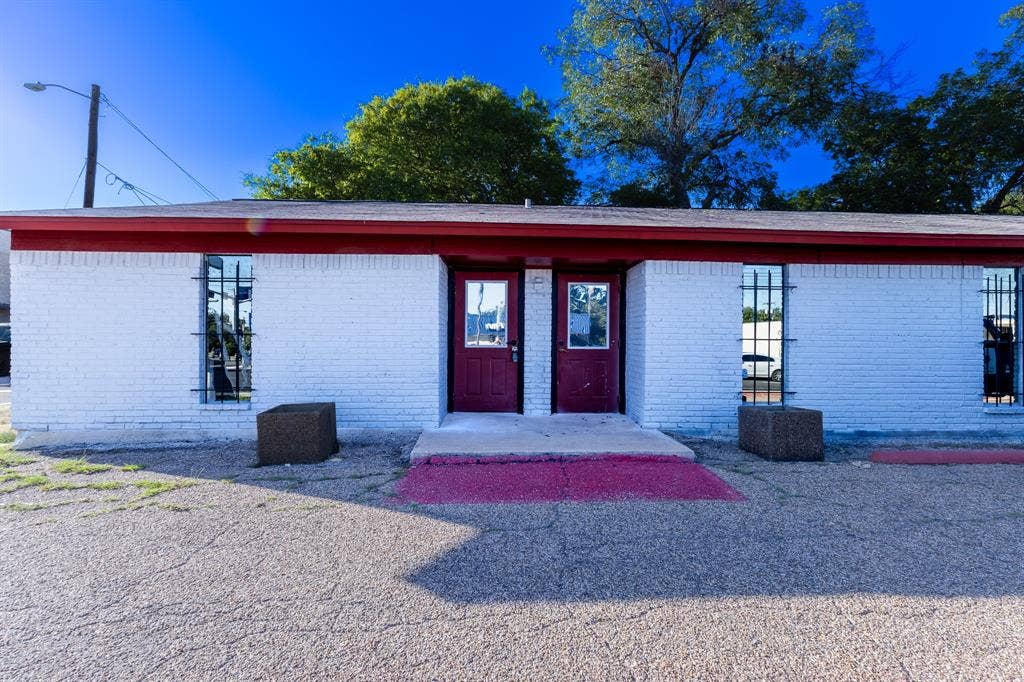 1723 W Waco Drive, #1725, Waco, TX 76707 White brick exterior with a red trim roofline, two entry doors, and windows with security bars