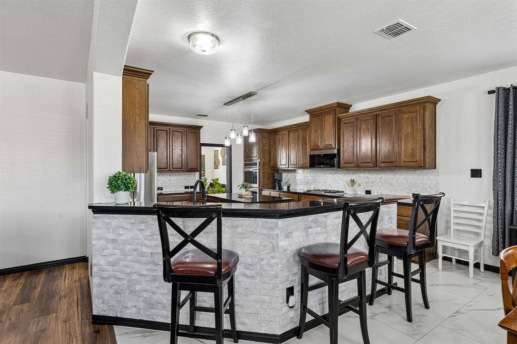 Convenient Casual Dining – The extended breakfast bar offers additional seating and serving space, with a stylish textured tile accent beneath the counter. Its open design keeps the kitchen connected to the breakfast area and family room.
