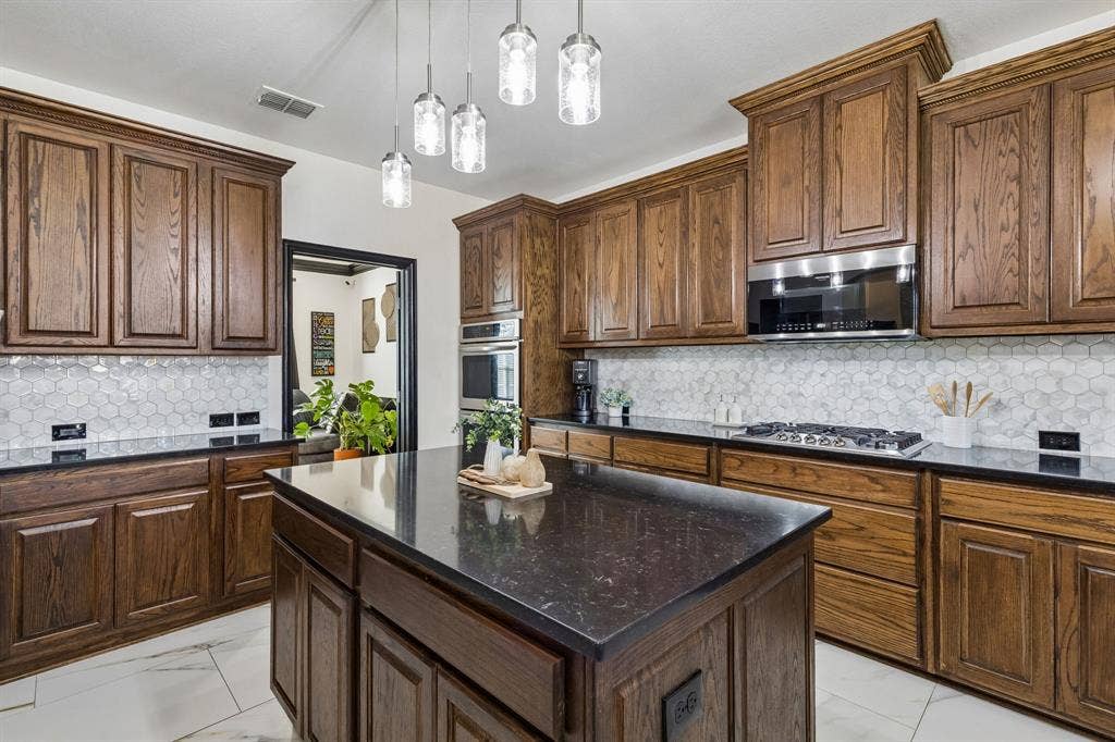 Equipped for Cooking – Stainless steel double ovens, a five-burner gas cooktop, and extensive cabinetry create a highly functional cooking space. Updated pendant lighting over the island adds a polished finishing touch.