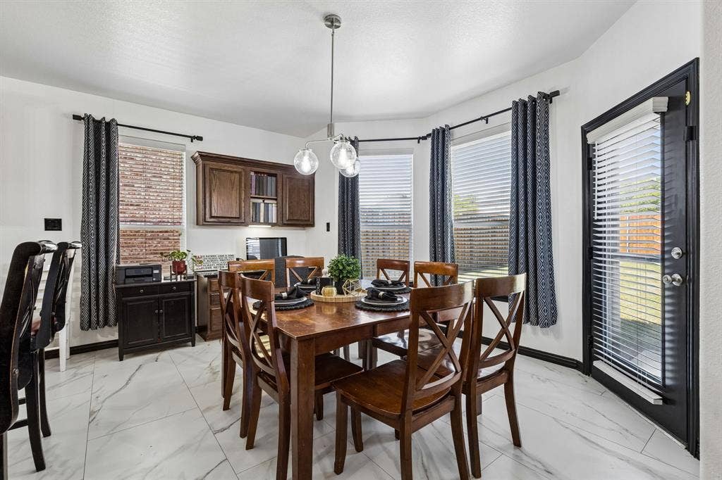 Bright and Inviting Breakfast Area – Surrounded by windows overlooking the backyard, this spacious casual dining area features updated lighting, attractive tile flooring, and a built-in desk with overhead cabinetry for added functionality