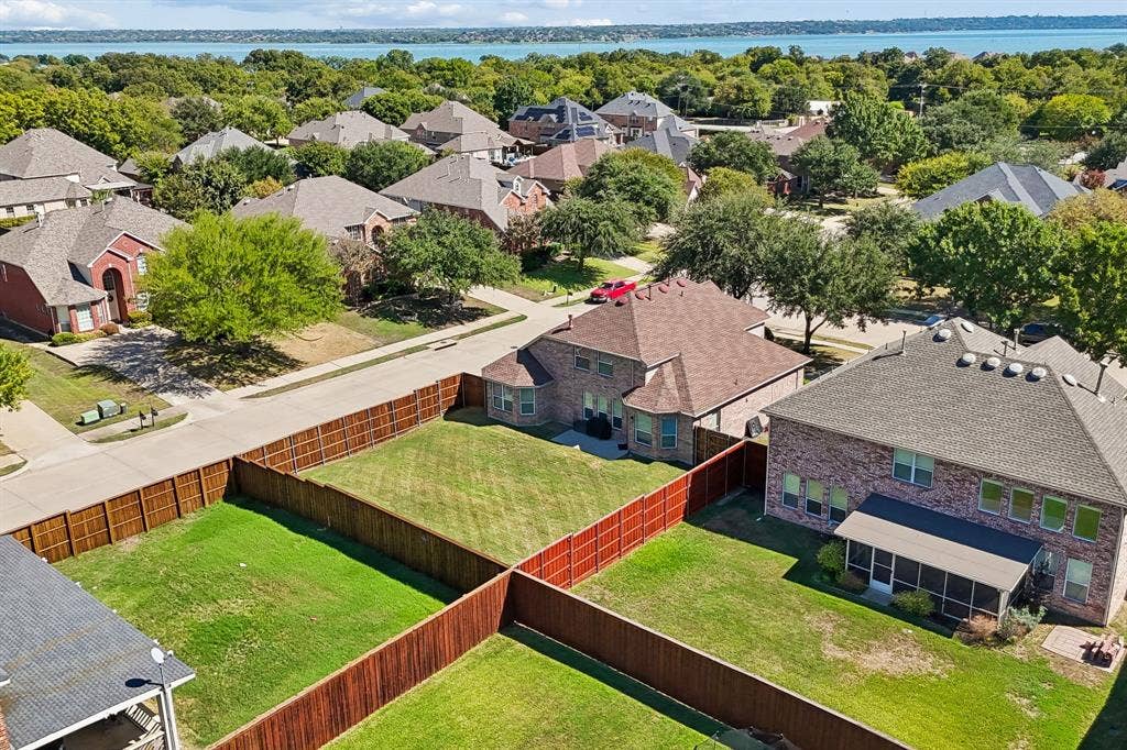 Enjoy the Waterview Lifestyle – This aerial perspective showcases the home's spacious backyard and established neighborhood setting, with beautiful Lake Ray Hubbard visible in the distance. Enjoy convenient access to lakeside recreation and everything the surrounding Rowlett area has to offer.