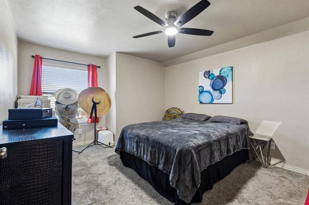 Generously Sized Secondary Bedroom – This spacious upstairs bedroom features soft carpeting, a large window for natural light, and an updated ceiling fan with integrated lighting, offering a comfortable space with flexible furniture arrangements