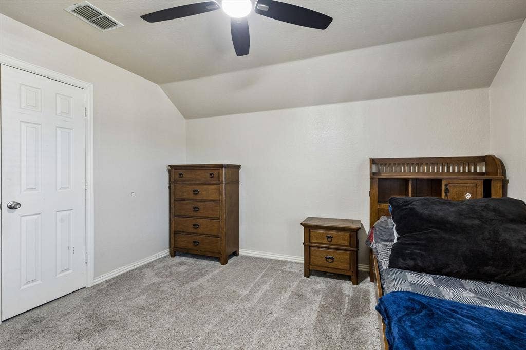 Comfortable Living with Room to Grow – Plush carpeting, neutral wall colors, and an angled ceiling detail create a welcoming atmosphere in this upstairs bedroom, with ample space for a larger bed and additional furnishings.