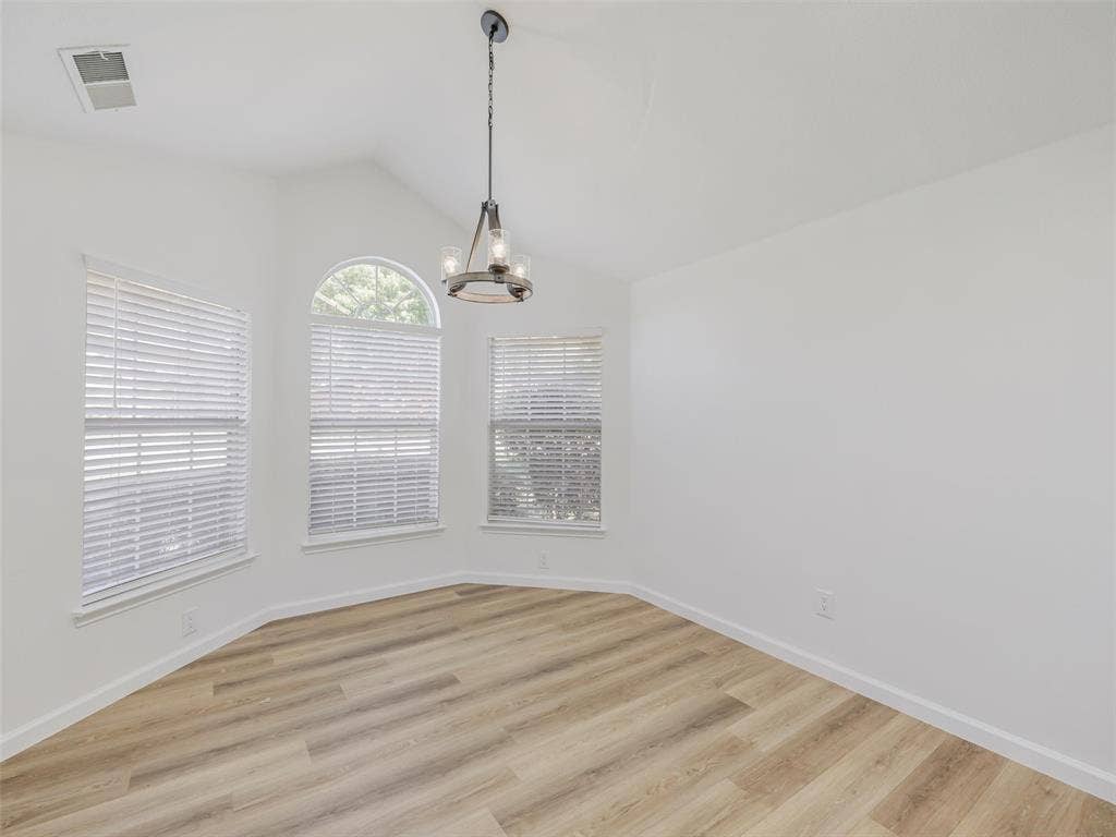 2327 N Ridge Road, McKinney, TX 75072 Vaulted ceiling with an industrial-style chandelier, arched window, multiple windows with blinds, and wood-finish flooring