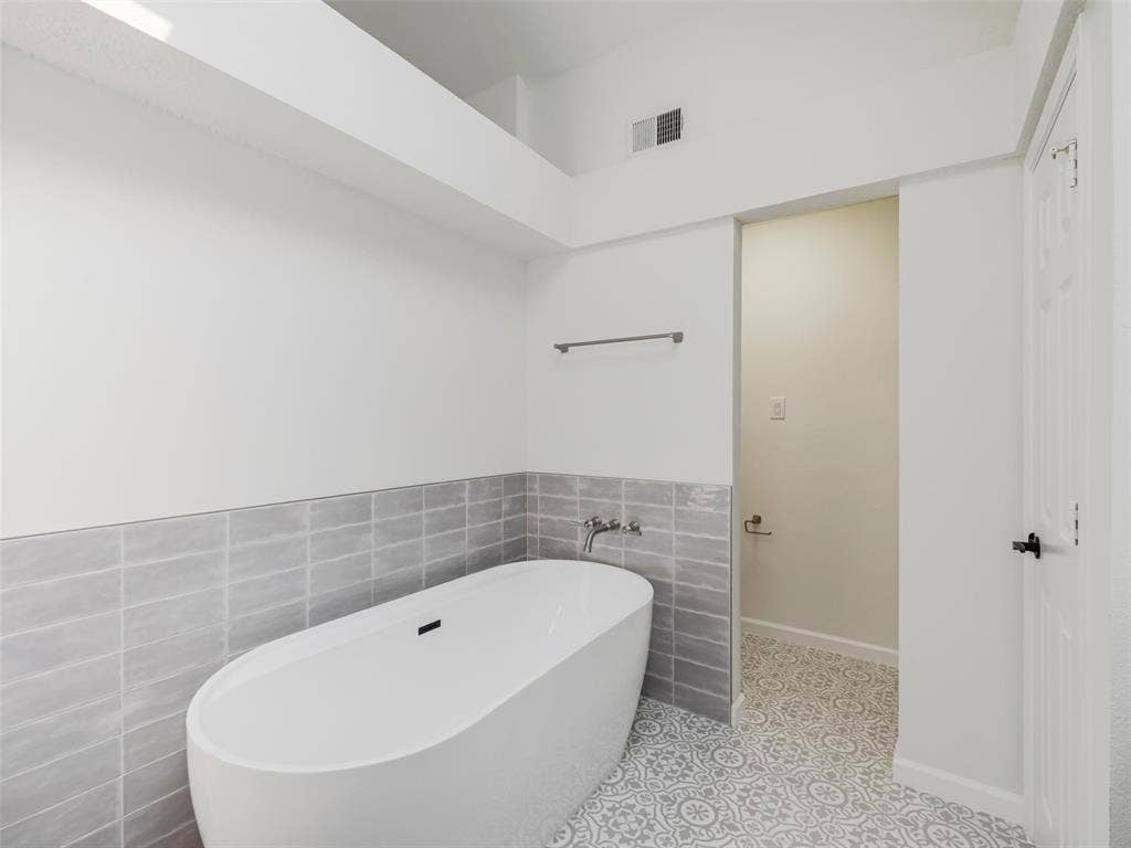 2327 N Ridge Road, McKinney, TX 75072 Freestanding soaking tub with wall-mounted faucet, subway tile wainscoting, and patterned floor tile