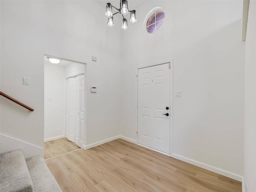2327 N Ridge Road, McKinney, TX 75072 Entryway featuring wood-finish flooring, a contemporary chandelier, a round transom window, and a paneled entry door with black hardware
